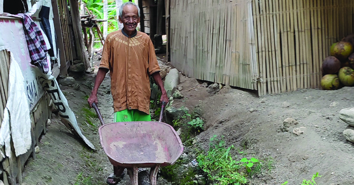 Indonesian villager, Rahim, using a wheelbarrow to help build a latrine
