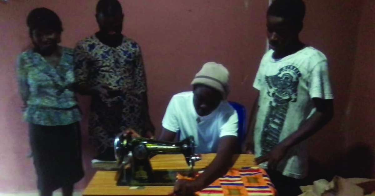 A young man sewing a bright and vibrant child outfit