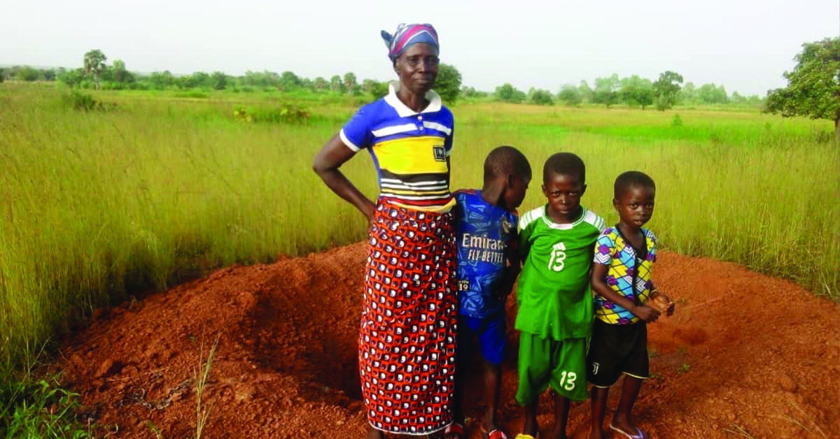 A mother and three boys behind a latrine site in progress.